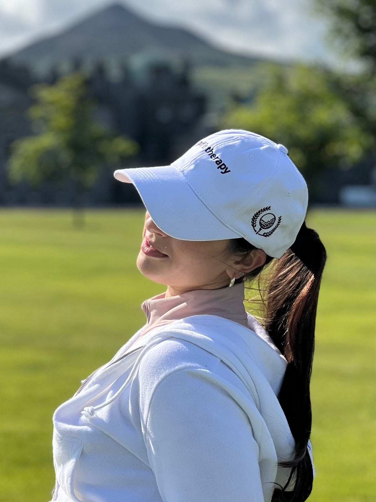 Aced It Co. Golf Is Therapy hat featuring a classic dad hat silhouette and golf-inspired design, modeled by a female golfer on the golf course